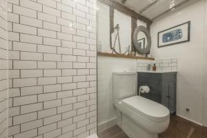 a white tiled bathroom with a toilet and a mirror at Well Green Cottage in Wenhaston