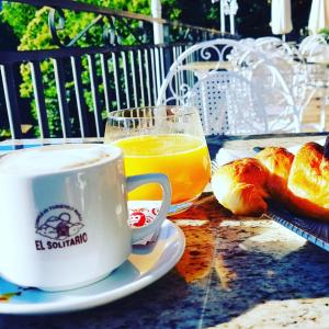 a table with a cup of coffee and a cup of orange juice at Albergue El Solitario in Baños de Montemayor