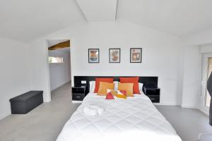 1 dormitorio con 1 cama blanca grande con almohadas de color naranja en Casa Rural Atabe Etxea, 