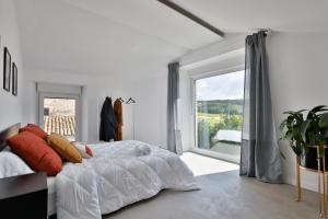 a white bedroom with a bed and a large window at Casa Rural Atabe Etxea 