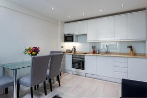 倫敦的住宿－Chic Apartment - Fabulous central location in Zone 1，厨房配有白色橱柜和桌椅