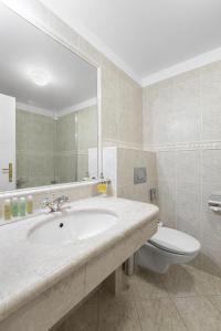 uma casa de banho com um lavatório, um WC e um espelho. em Hotel Patio Prague em Praga