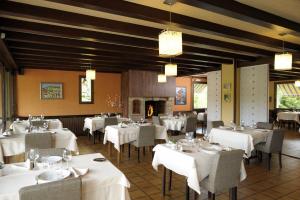 un restaurante con mesas y sillas blancas y chimenea en Le Relais De La Poste, en Neuvéglise