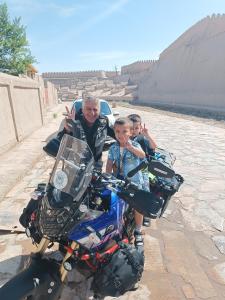 a man and two children sitting on a motorcycle at Khiva Ibrohim Guest House in Khiva