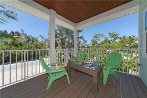 a porch with two green chairs and a table at Footprints in the Sand managed by Beach Retreats in Holmes Beach