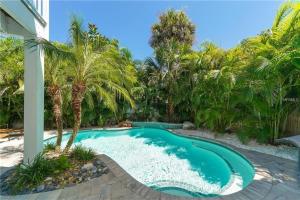 a swimming pool in a yard with palm trees at Footprints in the Sand managed by Beach Retreats in Holmes Beach +32 photos