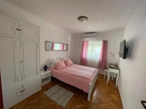 una camera da letto con un letto con lenzuola rosa e una finestra di Apartment Kati a Crikvenica