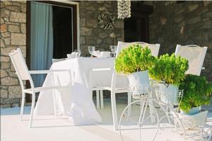 una mesa blanca con sillas blancas y macetas en White Diamond Villa, en Kamena Vourla