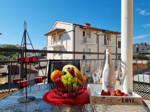 a table with a bowl of fruit and a bottle of wine at Apartments Medulin - Orijeta in Medulin