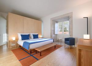 a bedroom with a large bed with blue pillows at Montebelo Mosteiro de Alcobaça Historic Hotel in Alcobaça