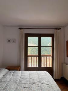 ein Schlafzimmer mit einem Bett und einem großen Fenster in der Unterkunft Casa planominguero in Taull