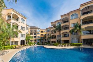 a swimming pool in front of some apartment buildings at Sunrise 33- 3 Bedroom Poolside Condo in Tamarindo