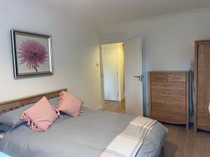 1 dormitorio con 1 cama con almohadas rosas y vestidor en Garden Flat, en Londres