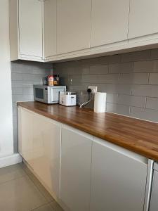 a kitchen with white cabinets and a counter with a microwave at Garden Flat in London