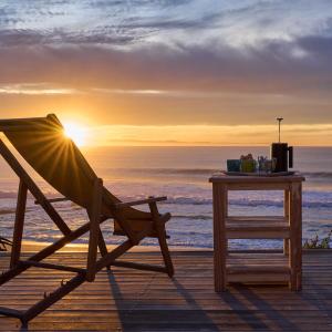 a deck with a chair and a table and the ocean at Soul Searchers in Jeffreys Bay