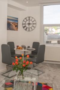 sala de estar con mesa, sillas y reloj en Church House - 2 Bed-Sleeps 4-TJS21CH, en Ilfracombe