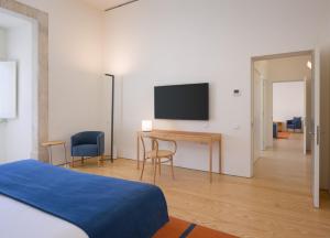 a bedroom with a bed and a desk with a tv at Montebelo Mosteiro de Alcobaça Historic Hotel in Alcobaça