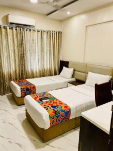Hotel Embassy Park - BKC Mumbai في مومباي: غرفة فندقية بسريرين واريكة