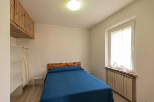 a bedroom with a blue bed and a window at Appartamento Per Due by HelloElba in Portoferraio
