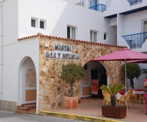 a restaurant in a building with an umbrella at Hostal Mar y Huerta in Es Cana