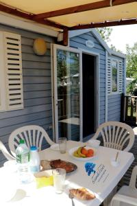 a table with a plate of food on a porch at Mobilhome «La mouette rieuse» * 6 personnes *Climatisatisé *2 Chambres in Sigean