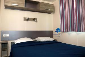a bedroom with a blue bed with two pillows at Mobilhome «La mouette rieuse» * 6 personnes *Climatisatisé *2 Chambres in Sigean