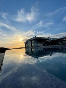 Cincinnato Wine Resort في Cori: مبنى به تجمع مياه امام غروب الشمس
