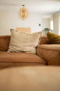 un divano marrone con un cuscino sopra di Vista del Mar Japandi a Koksijde