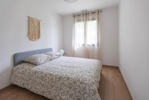 a white bedroom with a bed and a window at La Marssacoise in Marssac-sur-Tarn