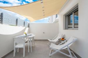 balkon z białymi krzesłami, stołem i oknem w obiekcie MEDANO4YOU Cabezo Residence w mieście El Médano