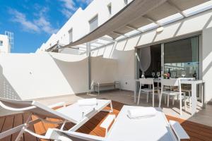balkon z białymi meblami, stołem i krzesłami w obiekcie MEDANO4YOU Cabezo Residence w mieście El Médano