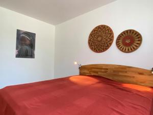ein Schlafzimmer mit einem Bett mit einer roten Decke und zwei Bildern an der Wand in der Unterkunft Ferienwohnung Heide-Tukkul in Hermannsburg