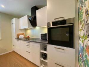 eine Küche mit weißen Schränken und einer großen Mikrowelle in der Unterkunft Ferienwohnung Heide-Tukkul in Hermannsburg