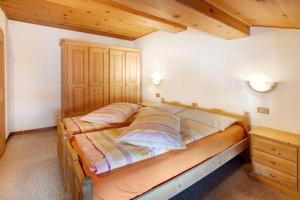duże łóżko w sypialni z drewnianymi sufitami w obiekcie Appartamenti Elisabetta n2 w Livigno