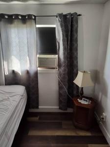1 dormitorio con 1 cama, cortinas y lámpara en Tranquil & Tasteful One Bdrm Private Suite NE, en Edmonton