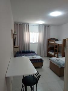 a small room with two beds and a table and chairs at Kitnet à 300 metros da Canção Nova in Cachoeira Paulista