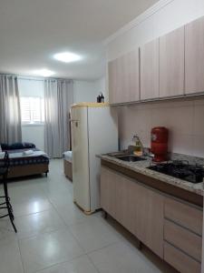 uma cozinha com um frigorífico branco e um fogão em Kitnet à 300 metros da Canção Nova em Cachoeira Paulista