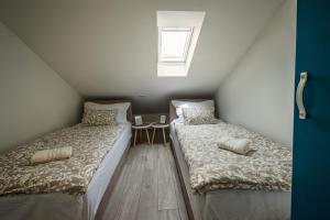two beds in a attic room with a window at Apartman I & J in Imotski