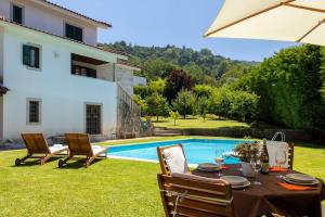 un patio con tavolo e sedie accanto alla piscina di casabraga.207 - Villa with Pool Bom Jesus a Braga