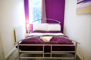 Cama en habitación con pared púrpura en Purple Blossom, cosy 2 bed apartment, near Didsbury, free parking, en Mánchester