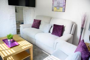 sala de estar con sofá blanco y almohadas moradas en Purple Blossom, cosy 2 bed apartment, near Didsbury, free parking, en Mánchester