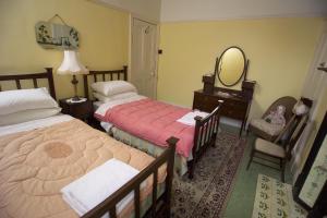 a bedroom with two beds and a mirror and a chair at Dylan Thomas House in Swansea