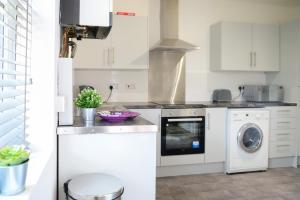 a kitchen with white cabinets and a washer and dryer at Purple Blossom, cosy 2 bed apartment, near Didsbury, free parking in Manchester