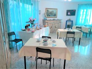 una sala da pranzo con tavoli e sedie bianchi di B & B Villa Fiorella a Termoli