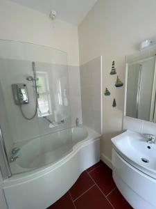 a white bathroom with a tub and a sink at The Cottage at Riverbank in Ballinamallard