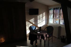 アルジュレス・ガゾストにあるLogis Hôtel Les Cimesの椅子2脚、テーブル、窓が備わる客室です。