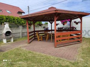 a wooden gazebo with a table and a grill at Domki Letniskowe Dominika in Gąski