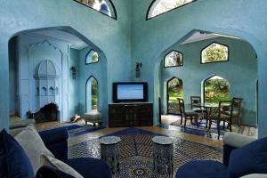 a living room with a tv and a table and chairs at Es Saadi Marrakech Resort - Palace in Marrakesh