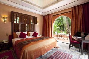 a bedroom with a bed and a desk and a window at Es Saadi Marrakech Resort - Palace in Marrakesh