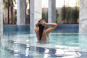 Una donna sta in piedi in una piscina di Es Saadi Marrakech Resort - Palace a Marrakech